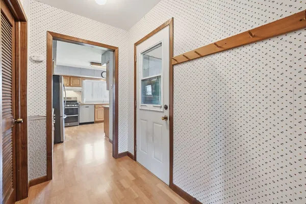 a view of a hallway with wooden floor and a bathroom