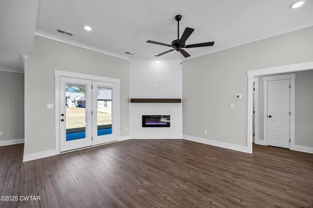 an empty room with wooden floor a ceiling fan and windows