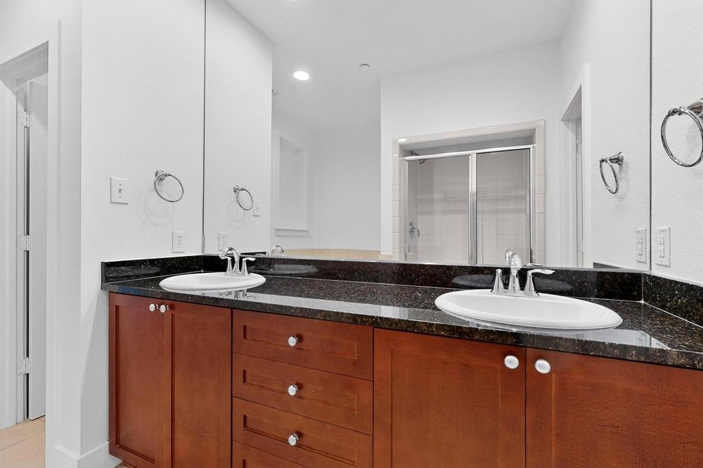 4211 Rawlins Street, Unit 528 Dallas, TX 75219 - Photo 8 of 14 Double vanity featuring wood-finish cabinetry, dark speckled countertops, and undermount sinks