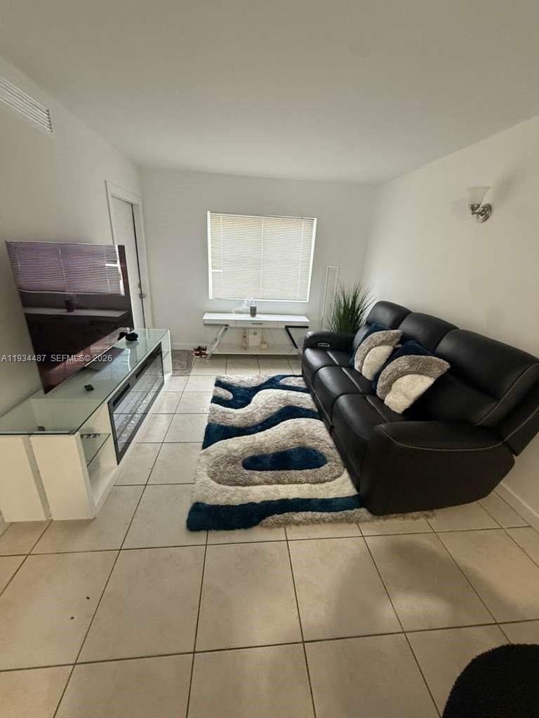 1250 Southeast 26th Street, Unit 102 Homestead, FL 33035 - Photo 2 of 16 a living room with furniture and a flat screen tv
