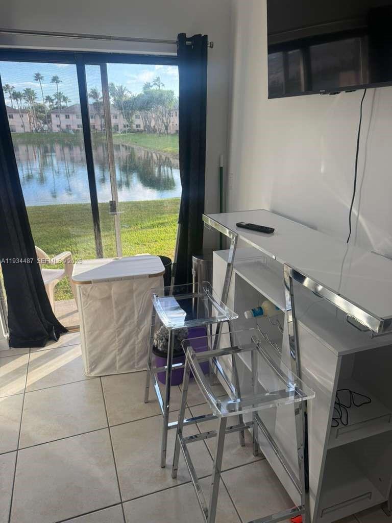1250 Southeast 26th Street, Unit 102 Homestead, FL 33035 - Photo 3 of 16 a living room with a floor to ceiling window and an outdoor view