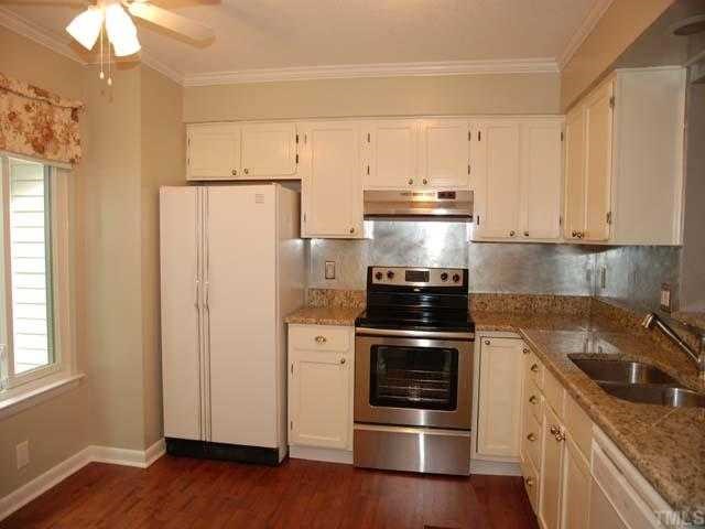 7612 Huey Court Raleigh, NC 27615 - Photo 2 of 6 a kitchen with a refrigerator stove and white cabinets with wooden floor