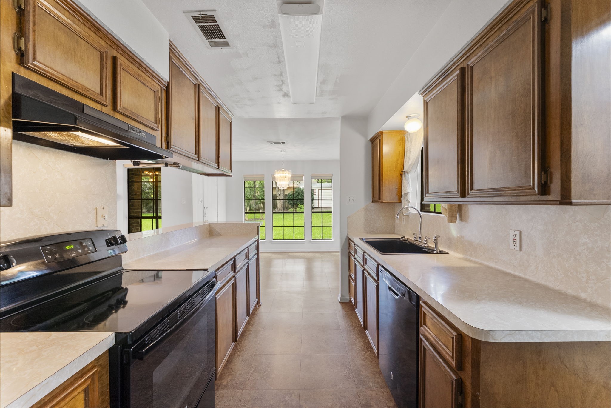 202 Sunset Boulevard Conroe, TX 77303 - Photo 19 of 50 This inviting kitchen boasts warm wooden cabinetry, modern appliances, and an open layout that seamlessly connects to a sunlit dining area with charming garden views.