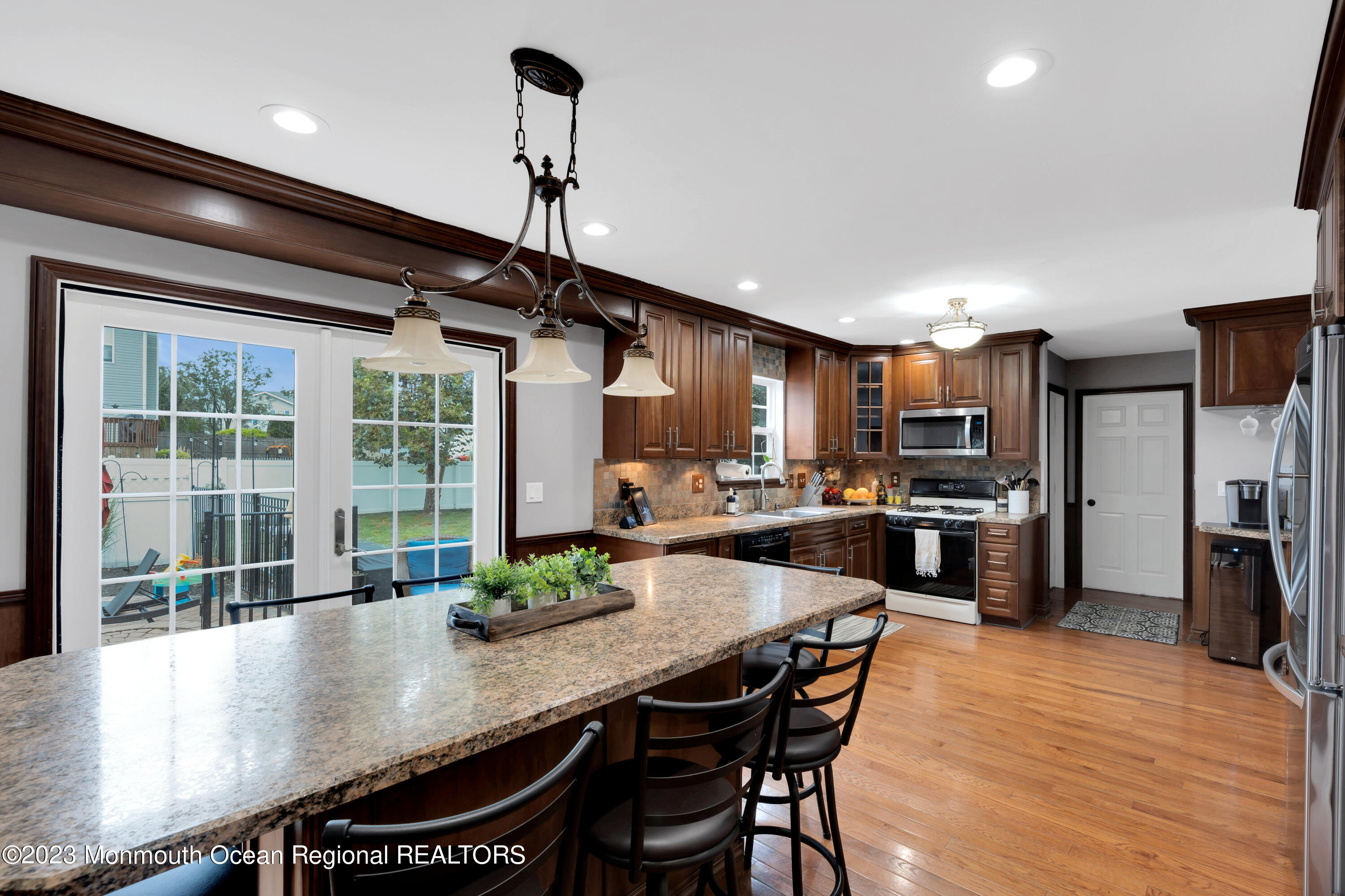 5 Autumn Drive Howell, NJ 07731 - Photo 18 of 50 a kitchen with stainless steel appliances granite countertop a stove a refrigerator a sink a dining table and chairs with wooden floor
