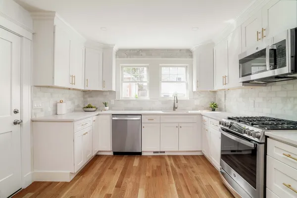 a kitchen with stainless steel appliances granite countertop a stove a sink and a microwave