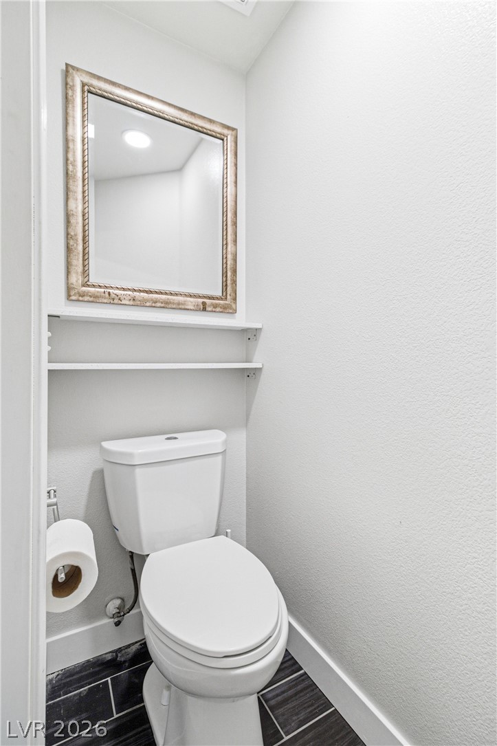 9523 Observer Street Las Vegas, NV 89123 - Photo 31 of 42 A compact powder room with a sleek white toilet and dark tiled flooring.