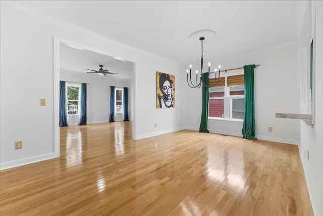 a view of an empty room with window and wooden floor