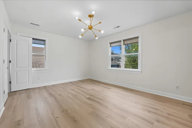 an empty room with wooden floor ceiling fan and windows
