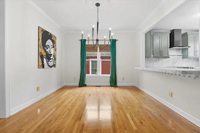 a view of empty room with wooden floor and kitchen view