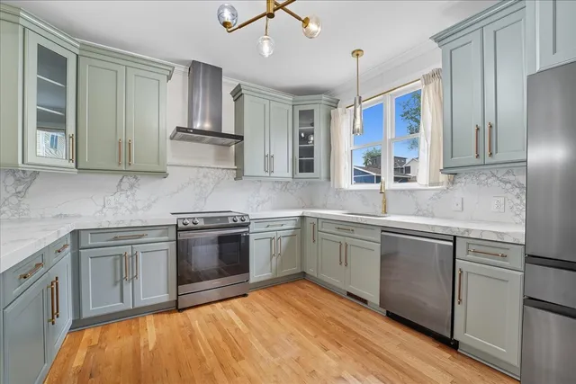 a kitchen with stainless steel appliances granite countertop a sink and stove top oven with wooden floor