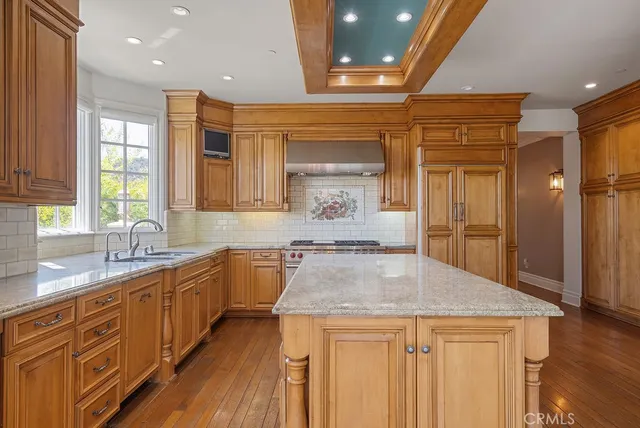 a kitchen with stainless steel appliances granite countertop a sink a stove and a wooden floors