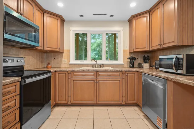 a kitchen with stainless steel appliances granite countertop a stove a sink and a microwave