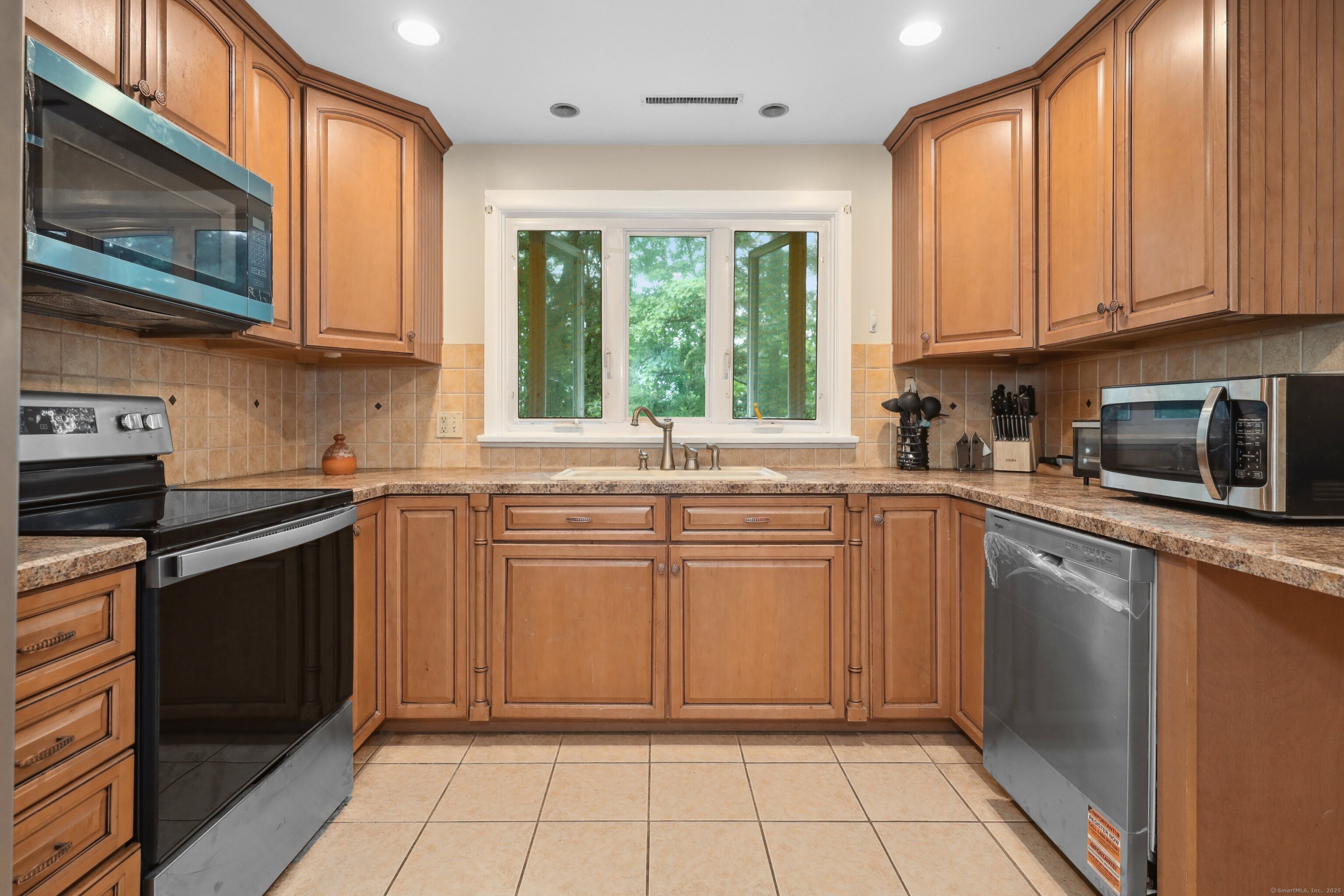 a kitchen with stainless steel appliances granite countertop a stove a sink and a microwave
