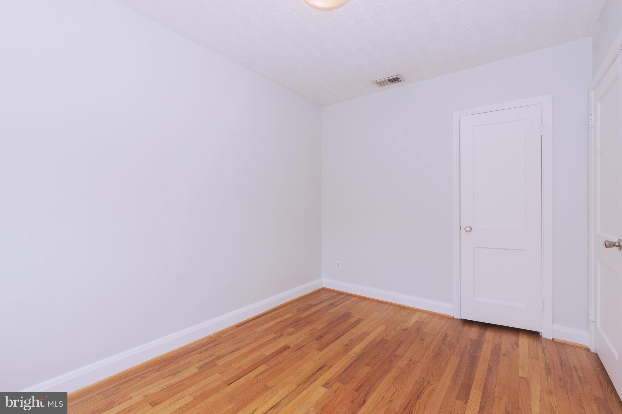 148 Wiltshire Road Baltimore, MD 21221 - Photo 18 of 28 a view of an empty room with wooden floor and a window