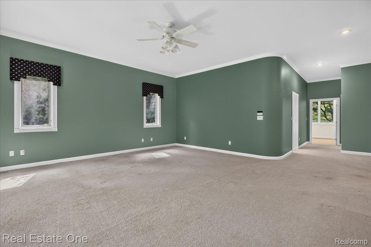 425 Courtney Road Leonard, MI 48367 - Photo 43 of 89 Spacious room featuring broadloom carpet, two windows with valances, a ceiling fan, and crown molding