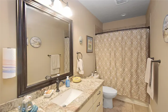 a bathroom with a granite countertop sink toilet and shower
