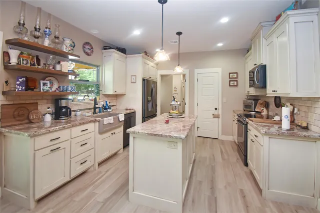 a large kitchen with stainless steel appliances kitchen island granite countertop a lot of counter space and wooden floors