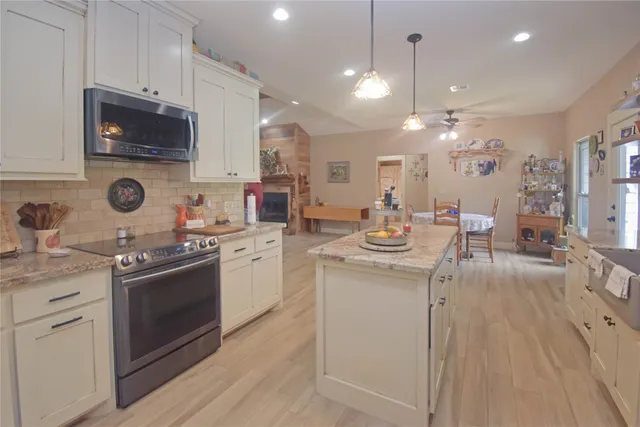 a kitchen with kitchen island granite countertop a sink appliances cabinets and a counter top space