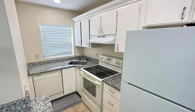a kitchen with granite countertop white cabinets and white appliances