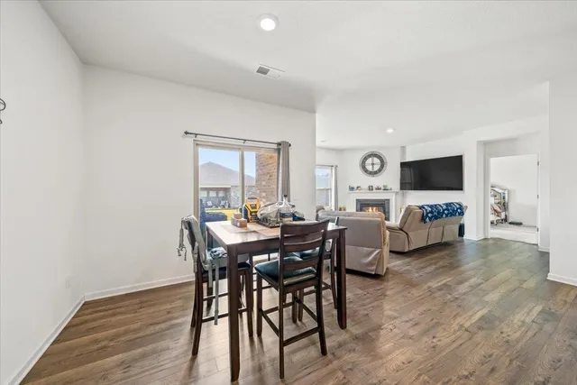 a kitchen with stainless steel appliances kitchen island granite countertop a refrigerator a stove a sink a dining table and chairs with wooden floor