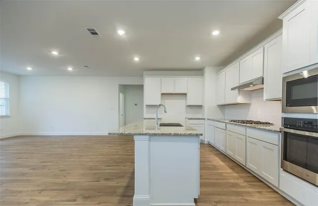 a large kitchen with stainless steel appliances granite countertop a stove a sink and a microwave