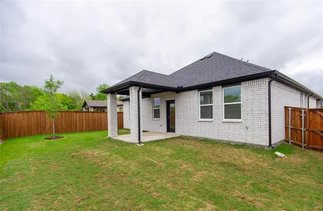 a front view of house with yard and trees in the background