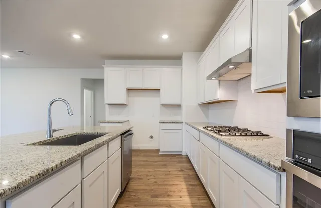 a kitchen with stainless steel appliances granite countertop a sink stove and cabinets
