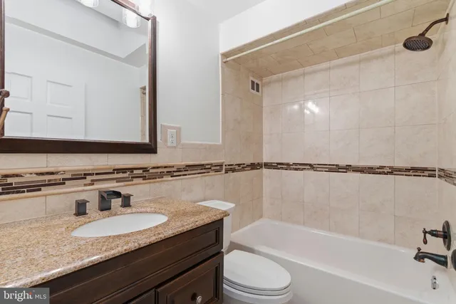 a bathroom with a granite countertop tub sink and mirror