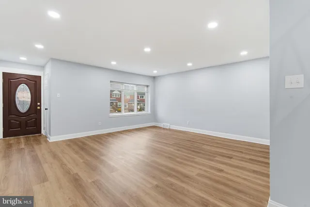 a view of an empty room with wooden floor and fan
