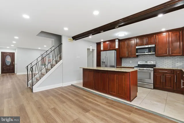 a kitchen with stainless steel appliances kitchen island granite countertop a stove a sink and a refrigerator