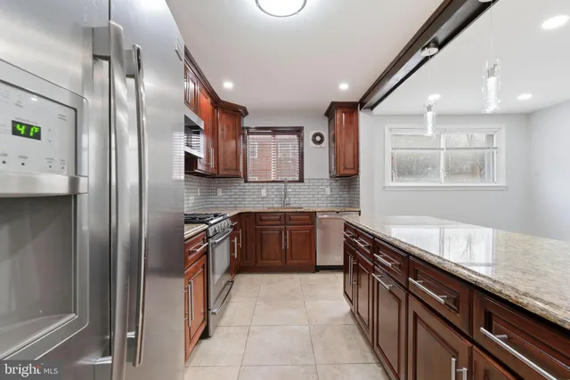 a kitchen with stainless steel appliances granite countertop a sink a stove and a refrigerator