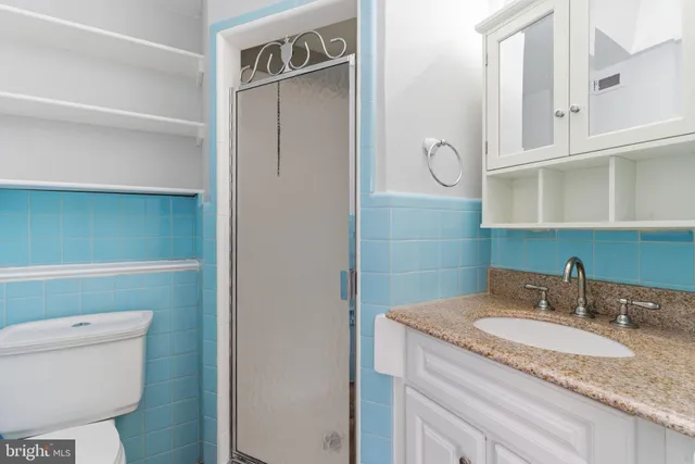 a bathroom with a granite countertop sink and a toilet