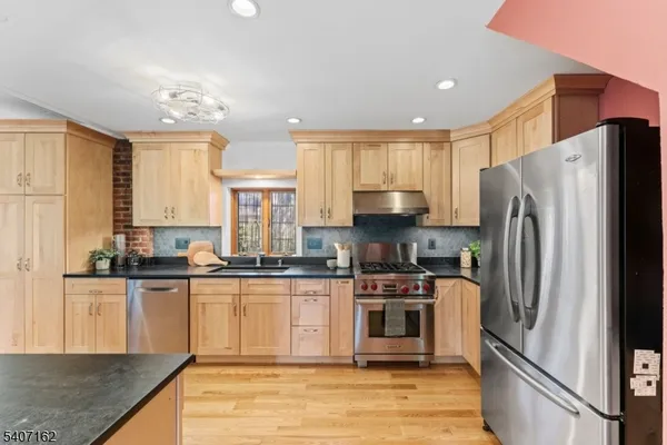 a kitchen with stainless steel appliances granite countertop a stove a sink dishwasher and a microwave oven with large wooden cabinets