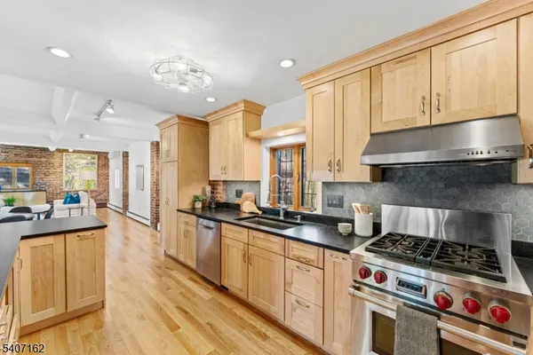 a view of a kitchen with kitchen island granite countertop a large window cabinets a sink and stainless steel appliances