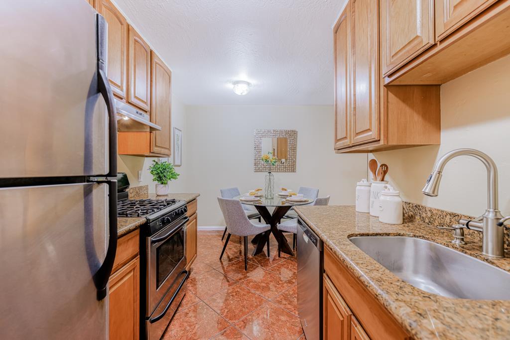 38455 Bronson Street, Unit 322 Fremont, CA 94536 - Photo 11 of 35 a kitchen with stainless steel appliances granite countertop a sink stove and cabinets