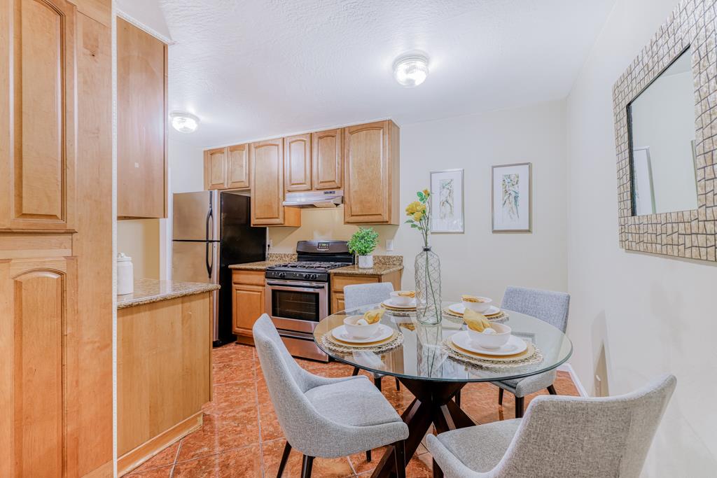 38455 Bronson Street, Unit 322 Fremont, CA 94536 - Photo 6 of 35 a kitchen with stainless steel appliances kitchen island granite countertop a dining table and chairs with wooden floor