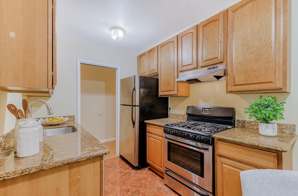 38455 Bronson Street, Unit 322 Fremont, CA 94536 - Photo 9 of 35 a kitchen with stainless steel appliances granite countertop a sink stove and refrigerator