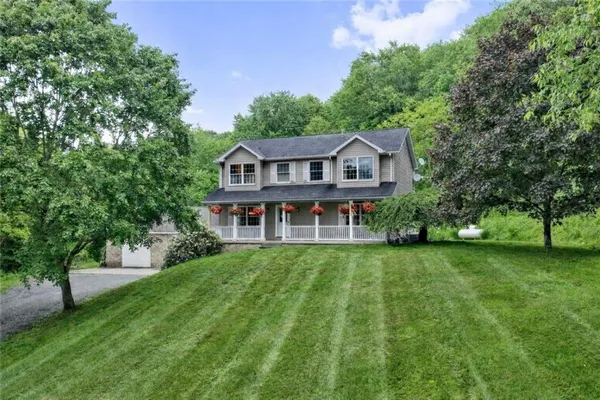 a view of a big house with a big yard and large trees