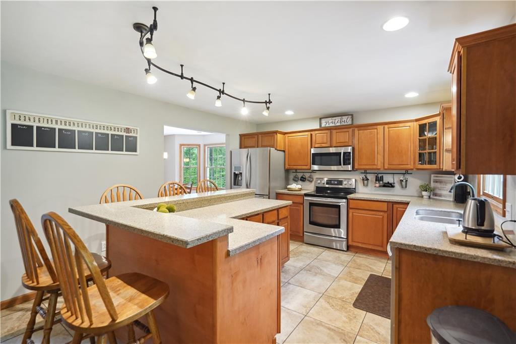 565 Leeper Road Georgetown, PA 15043 - Photo 8 of 46 a kitchen with stainless steel appliances granite countertop a sink a stove a refrigerator a microwave oven with a dining table and chairs