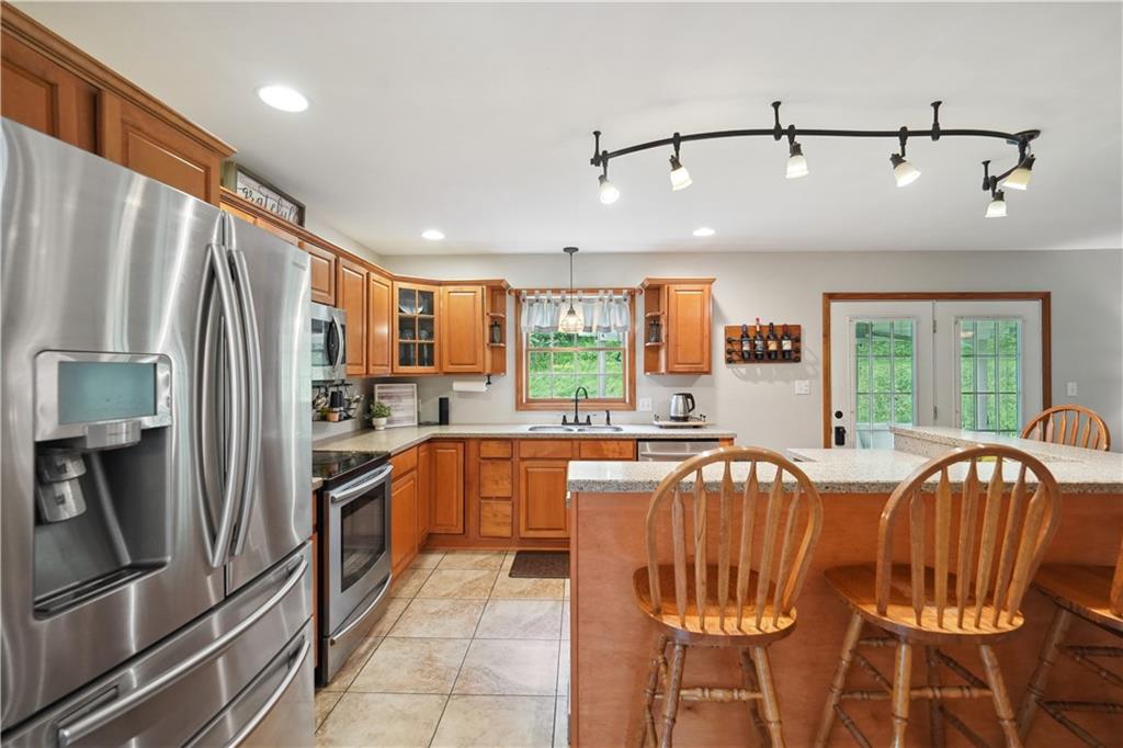 565 Leeper Road Georgetown, PA 15043 - Photo 9 of 46 a kitchen with stainless steel appliances granite countertop a refrigerator a sink dishwasher a stove with white cabinets and wooden floor