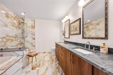 a bathroom with a granite countertop sink a mirror a bathtub and next to a window