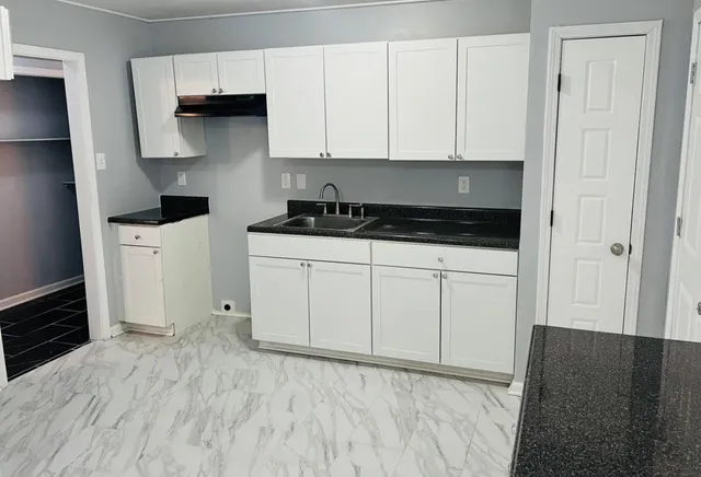 a kitchen with white cabinets and sink
