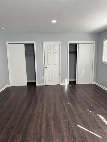 a view of an empty room with wooden floor and closet