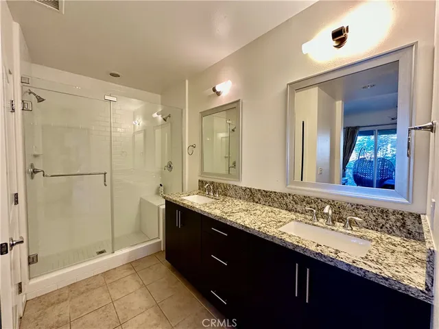 a bathroom with a granite countertop sink a mirror and a shower