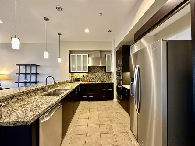 a kitchen with granite countertop a refrigerator a sink and white cabinets