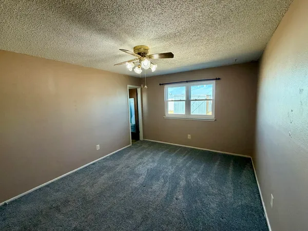 an empty room with a window and a fan