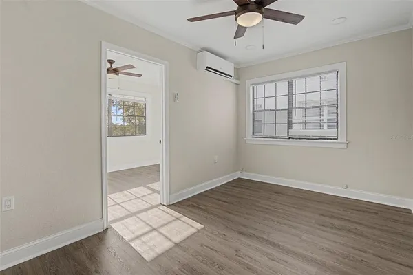 an empty room with wooden floor chandelier fan and windows
