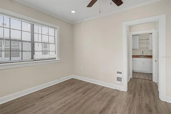 a view of empty room with wooden floor and fan