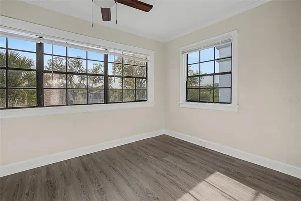 a view of empty room with wooden floor and fan