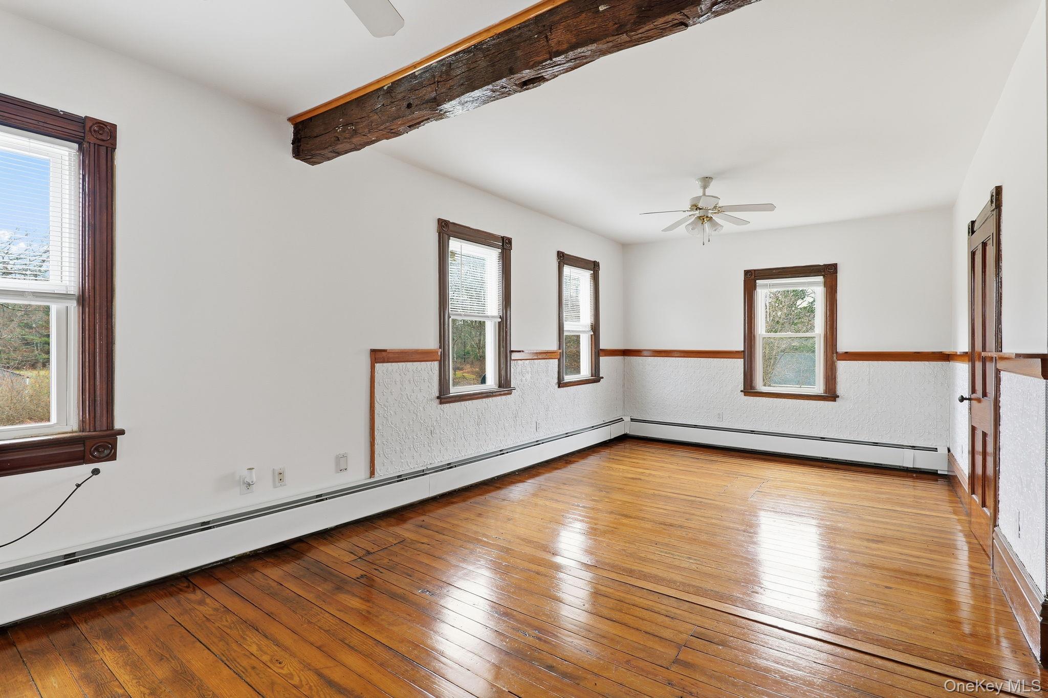 708 Burlingham Road Bloomingburg, NY 12721 - Photo 15 of 25 Unfurnished room featuring a baseboard radiator, ceiling fan, hardwood / wood-style flooring, and beamed ceiling